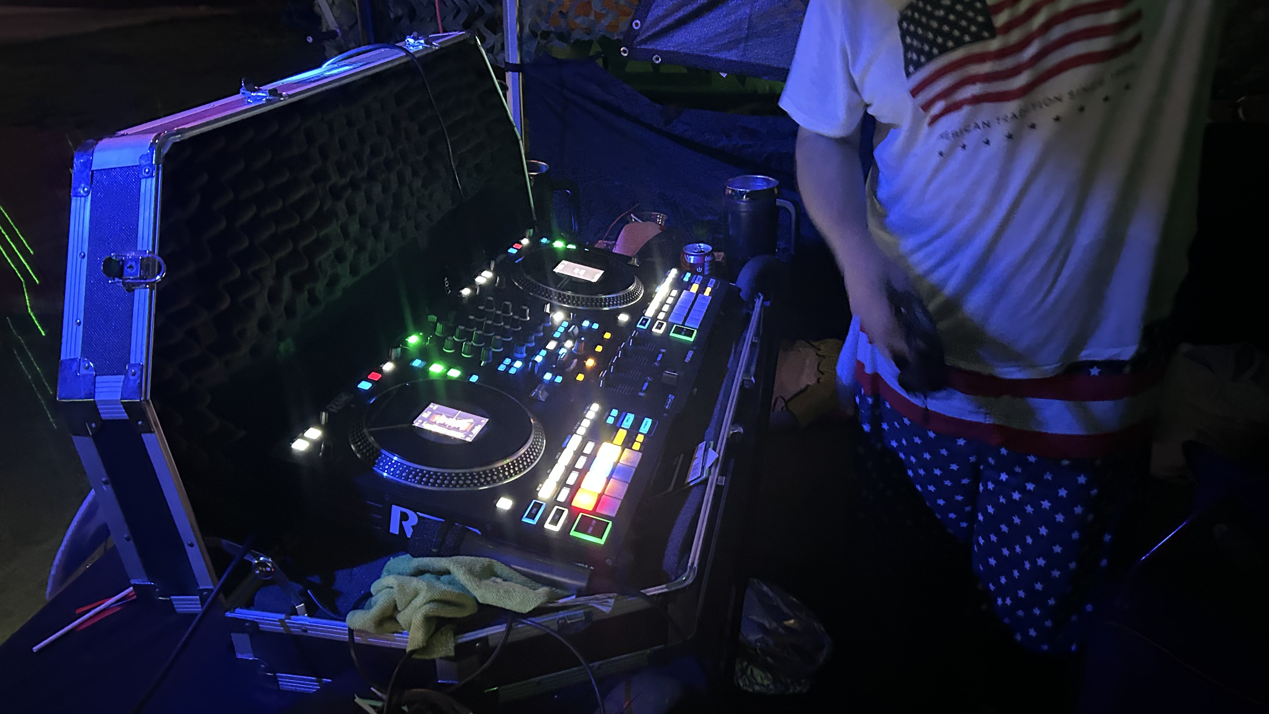 DJ mixing under blue and green stage lighting